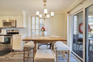 Une cuisine équipée d’un four à micro-ondes, d’une cuisinière et d’un four, une table à manger avec des sets de table et un lustre.