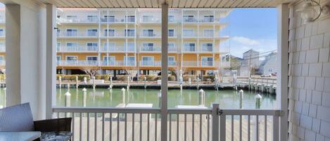 A balcony with a view of a water body and a multi-story building in the background.