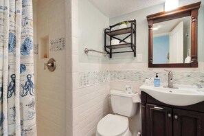 Une salle de bain équipée de toilettes, d’un lavabo, d’un miroir, d’un porte-serviettes et d’un rideau de douche.