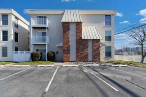 Un immeuble à plusieurs étages, doté d’une façade en briques, d’un balcon au deuxième étage et d’un parking situé à l’avant.