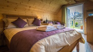 A wooden cabin bedroom with a bed, pillows, a nightstand, and a window. - Bidean - Cosy Eco Cabin with stunning views (Leacantuim, Glencoe)