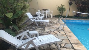 Area piscina con lettini, un tavolino e una rete da pallavolo.
