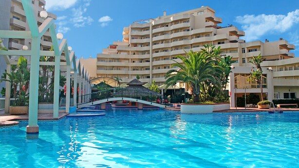 Ein Hotel mit Schwimmbad, Brücke und mehreren Balkonen.
