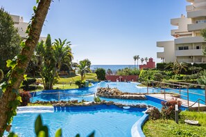 A pool area with multiple water features, surrounded by greenery and buildings. - Rental BB 916-3 in Benalm Dena (Benalmádena)