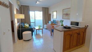 Uma sala de estar moderna com um sofá, uma mesa de centro e um espaço de jantar com uma ilha pequena.