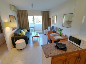 A living room with a sofa, coffee table, dining table, and kitchen area with a microwave and cabinets. - Rental BB 436-3 in Benalm Dena (Benalmádena)