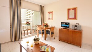 A hotel room with a dining area, a TV, a wooden cabinet, and a balcony with curtains. - Rental BB 436-3 in Benalm Dena (Benalmádena)