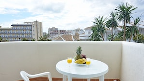 A balcony with a round table, two chairs, a fruit bowl with a pineapple, and two glasses of orange juice. - Rental BB 436-3 in Benalm Dena (Benalmádena)