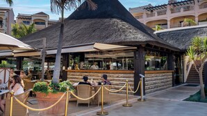 Un resort con una struttura a tetto di paglia, posti a sedere all'aperto e un'area bar.