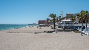 Una spiaggia con un edificio bianco, palme e un cielo azzurro limpido.