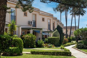 Un edificio con jardín, un sendero y palmeras.