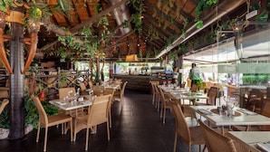 An indoor restaurant with wooden tables and chairs, a bar area, and hanging plants. - AS PM 28A in Mijas Costa (Mijas)