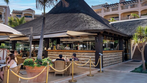 A resort with a thatched-roof structure, outdoor seating, and a bar area. - AS PM 28A in Mijas Costa (Mijas)