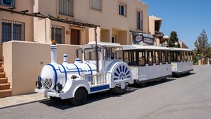 Ett vitt och blått fordon som liknar ett tåg står parkerat framför en byggnad med en skylt där det står ”Sorrento”.