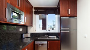 A kitchen with a Bosch microwave, dishwasher, and refrigerator, wooden cabinets, granite countertop, and a window with blinds. - AS MM C08 in Mijas Costa (Mijas)