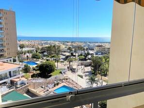Ein Wohngebiet mit Schwimmbad, Palmen und Blick aufs Meer.