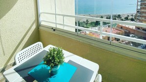 A balcony with a view of the sea, a potted plant, and a table with a chair. - Tamarindos 1002 in Benalm Dena (Benalmádena)