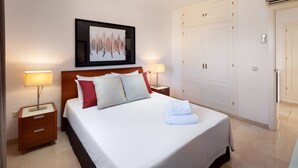 A neatly made bed with pillows, a bedside lamp, a framed artwork above the bed, and a wardrobe in the background. - AS MDS 112 in Mijas Costa (Mijas)