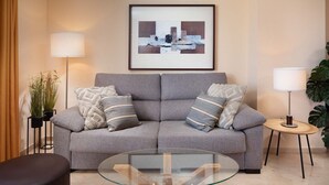 A living room with a grey sofa, two side tables with lamps, a glass coffee table, and a framed abstract painting on the wall. - AS MD 3C3 in Mijas Costa (Mijas)