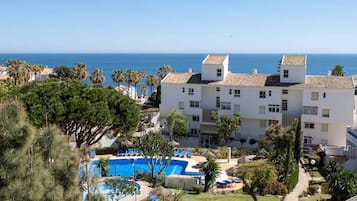Een resort met een zwembad, ligbedden en uitzicht op zee.