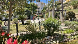 A garden with a playground, palm trees, and a water feature. - AS EXT Calanova 71A in Mijas Costa (Mijas)