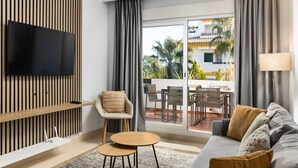 A modern living room with a flat-screen TV, a sofa, a round wooden table, and a chair. - AS EXT Calanova 71A in Mijas Costa (Mijas)