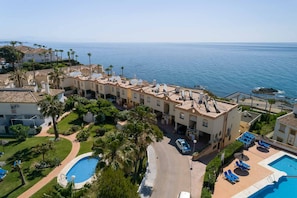 Un hotel costero con varias construcciones, piscina y vista al mar.