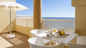 Un balcone con un tavolo apparecchiato per la colazione, con croissant, un bicchiere di succo d'arancia e una tazza.