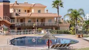 A swimming pool with lounge chairs, a lifebuoy, and a thatched umbrella. - AS MM C10 in Mijas Costa (Mijas)