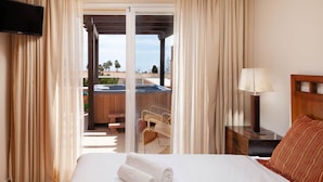 A hotel room with a bed, a TV, a lamp, a wooden nightstand, and a view of a pool and outdoor seating area. - AS MM C10 in Mijas Costa (Mijas)