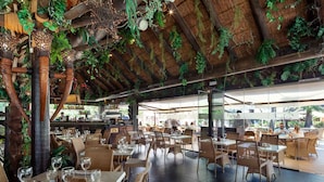 An outdoor dining area with tables and chairs, a thatched roof, and hanging plants. - AS LJ D 3 A in Mijas Costa (Mijas)