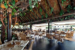 An outdoor dining area with tables and chairs, a thatched roof, and hanging plants. - AS LJ D 3 A in Mijas Costa (Mijas)
