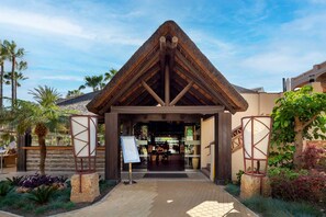 A building entrance with a thatched roof, palm trees, and a paved walkway. - AS LJ D 3 A in Mijas Costa (Mijas)