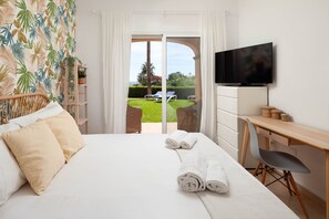 A hotel room with a bed, a desk, a TV, and a view of a lawn and palm trees. - AS LJ D 3 A in Mijas Costa (Mijas)