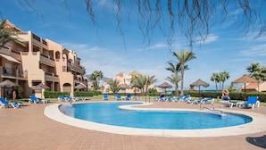 A swimming pool with blue lounge chairs, palm trees, and a hotel building in the background. - AS LJ D 3 A in Mijas Costa (Mijas)