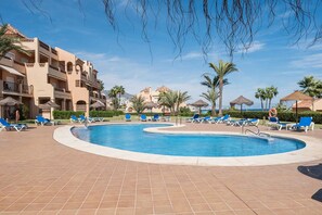 A swimming pool with blue lounge chairs, palm trees, and a hotel building in the background. - AS LJ D 3 A in Mijas Costa (Mijas)