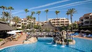 A resort pool with palm trees, lounge chairs, and a bridge. - AS MDM 5 in Mijas Costa (Mijas)