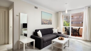 Een moderne woonkamer met een zwarte bank, een witte salontafel en een eethoek met stoelen en een tafel.