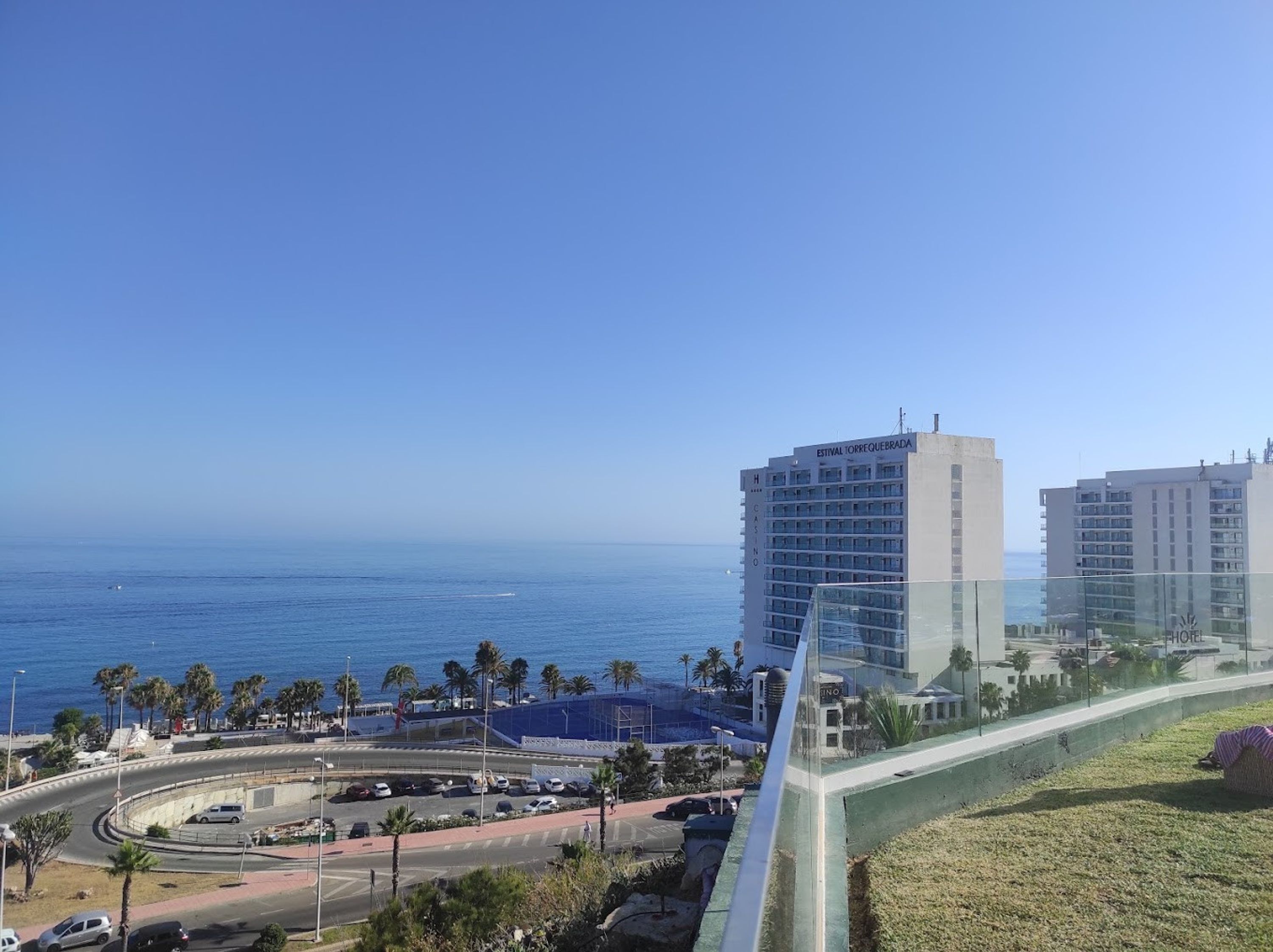 Ein Hotel an der Küste mit Blick auf das Meer, einem Parkplatz und einem Fußweg.