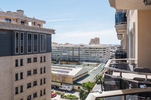 A high-rise building with multiple balconies, a parking area, and a view of other buildings in the distance. - Boliches Mediterraneo Real Tropical by Alfresco Stays (Fuengirola)