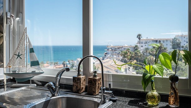 Una cocina con vista al mar, un modelo de barco y dos jarrones.