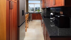 Una cocina moderna con armarios de madera, un refrigerador de acero inoxidable, una cafetera y vistas a través del ventanal.