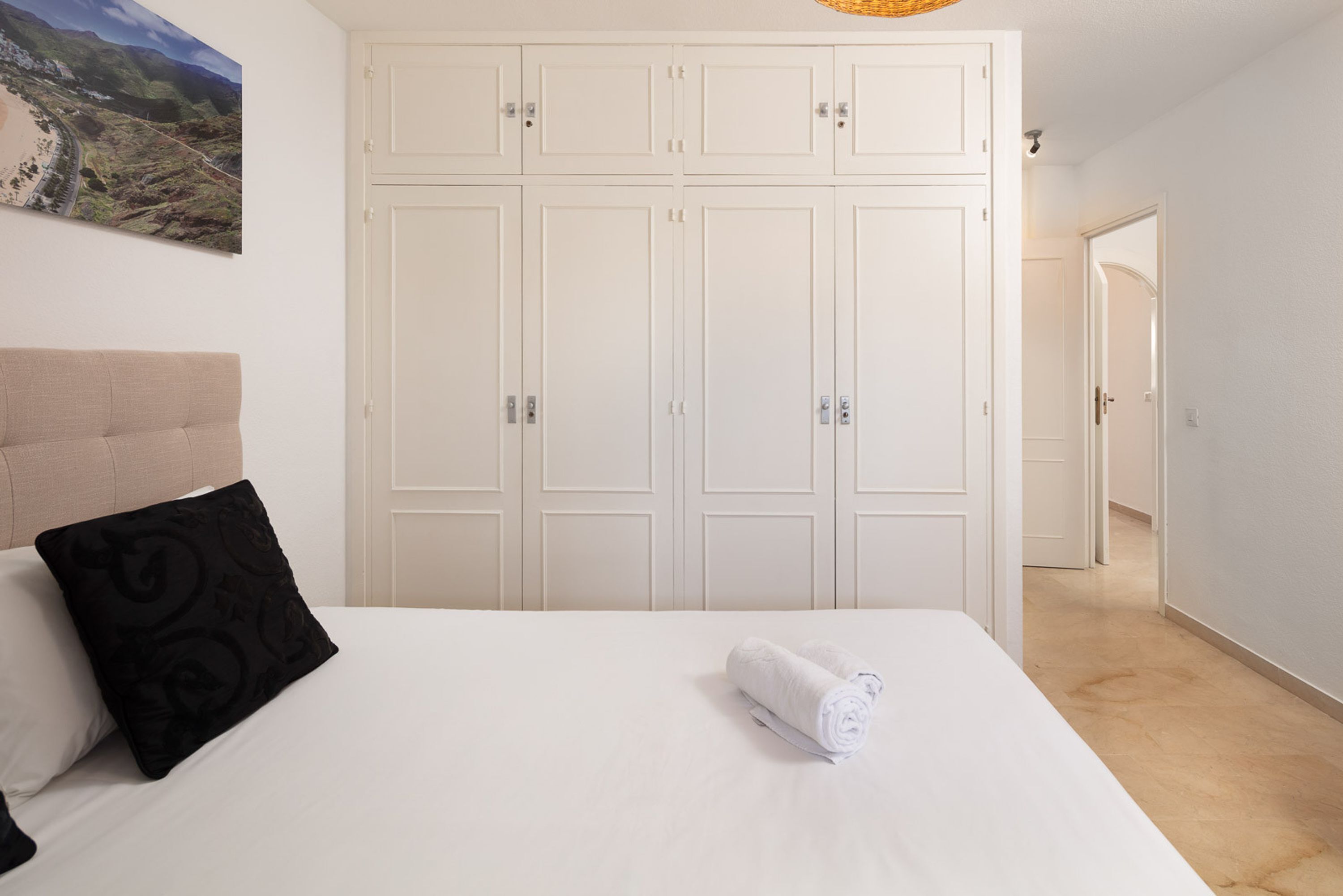 Una camera da letto con un letto, una testiera, un ampio armadio e un quadro appeso al muro.