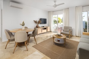 Una sala de estar moderna con una mesa de comedor, sillas, un sofá, un televisor y un ventilador de techo.