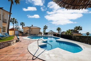 Ein Pool mit geschwungener Form, Liegestühle und Palmen.