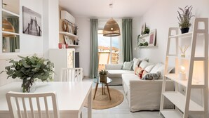 A modern living room with a white sofa, a dining table with chairs, a coffee table, and a large window with curtains. - AS EXT AL 2B1 3 1 in Mijas Costa (Mijas)