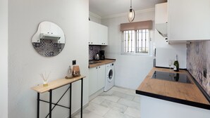 Uma cozinha moderna com máquina de lavar, cafeteira e uma garrafa de vinho.