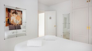 A hotel room with a large bed, a painting on the wall, a door with a small emblem, and a mirror. - AS MDS 133 in Mijas Costa (Mijas)