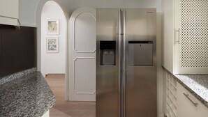 A stainless steel refrigerator in a kitchen with granite countertops and white cabinetry. - AS EXT CBP Samisol FI 2 (Marbella)