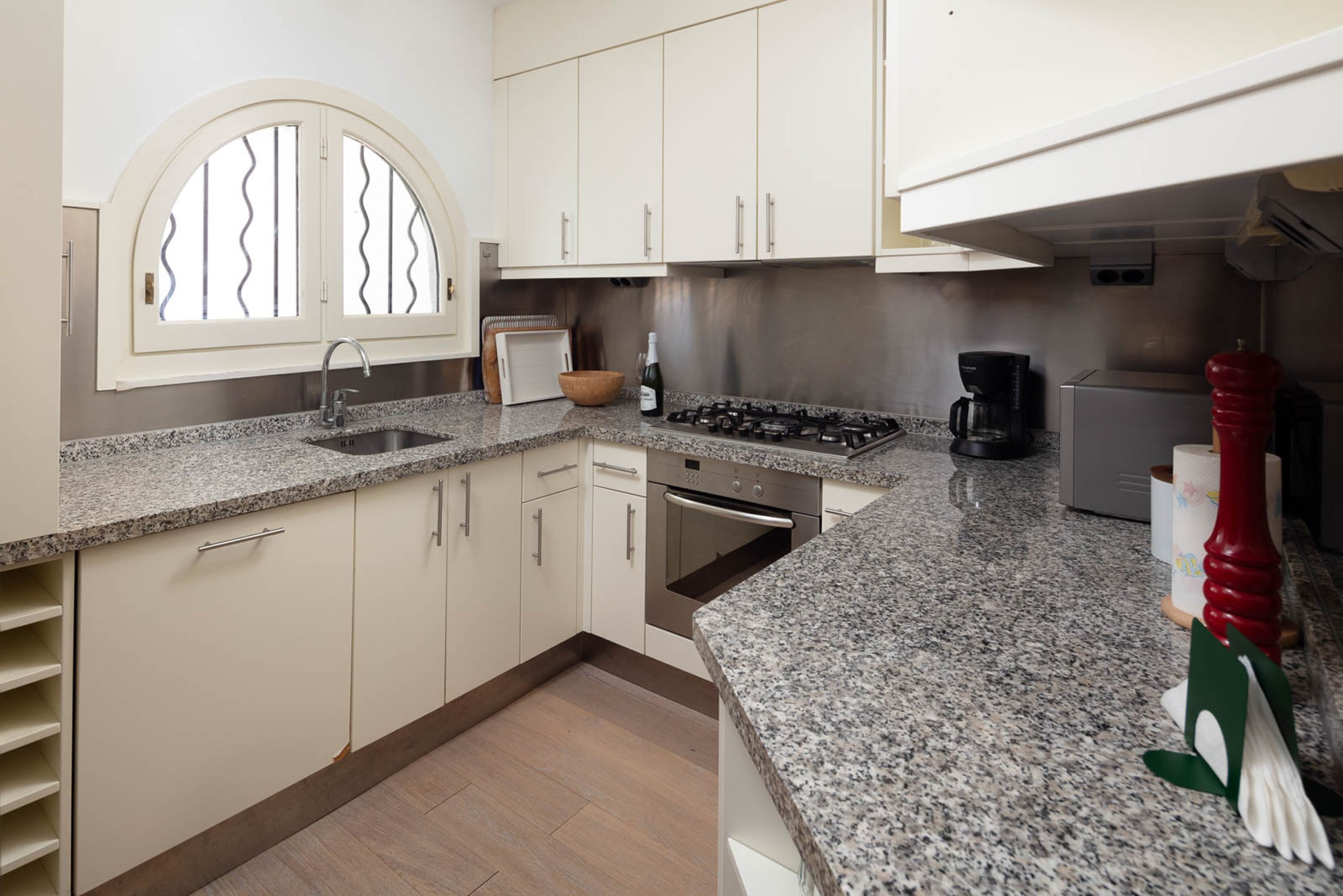 A kitchen with a granite countertop, stainless steel appliances, and white cabinetry.